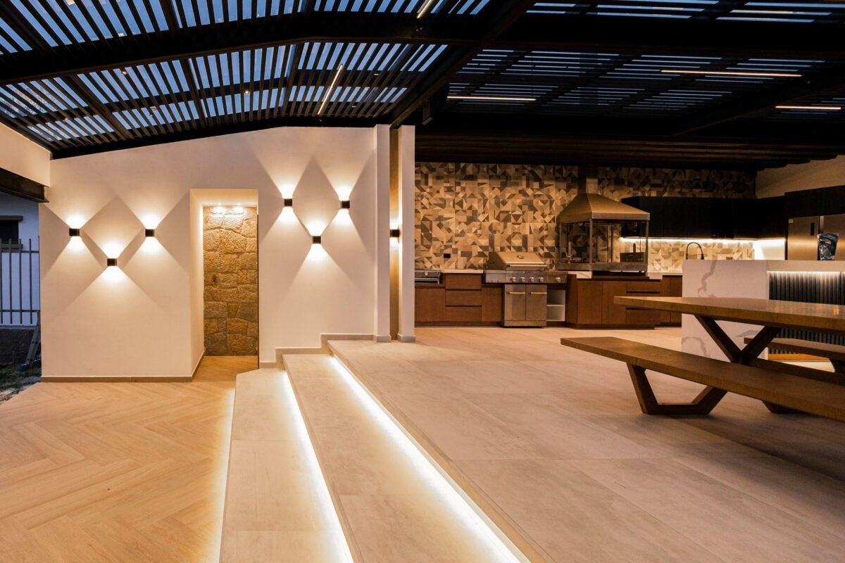 Área gourmet contemporânea integrada com cozinha externa e iluminação sofisticada